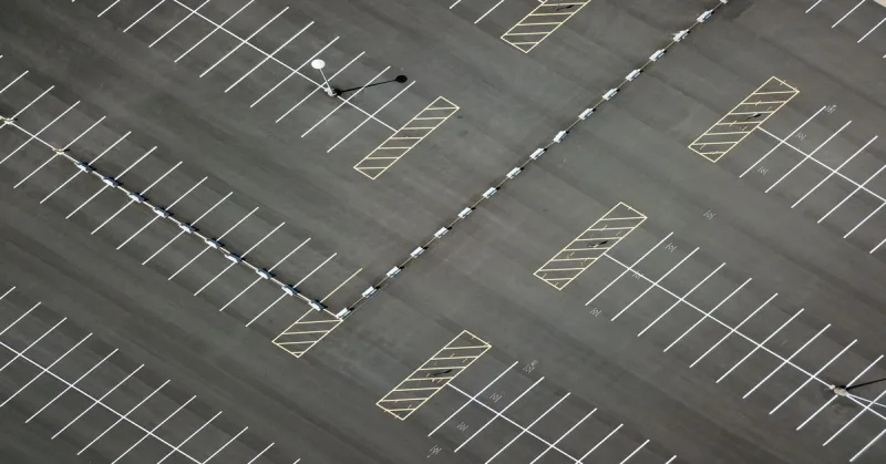 Vue plongeante d’un parking extérieur vide aux places délimitées
